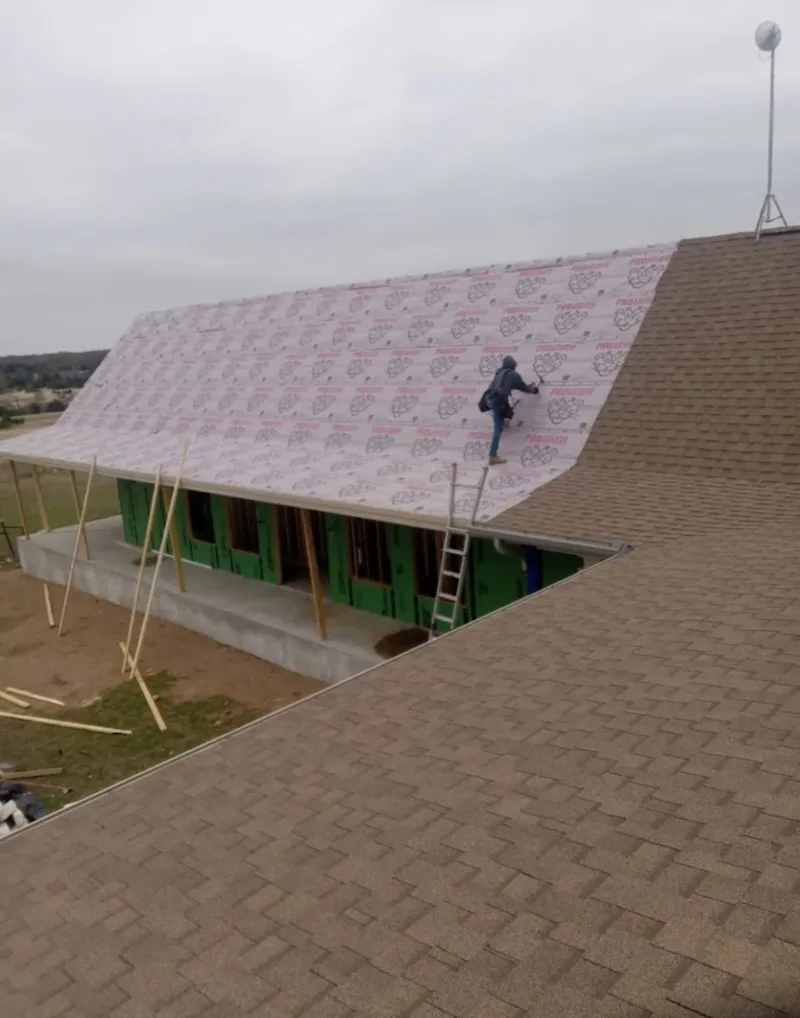 Worker preparing underlayment for a metal roof installation in Ludlow